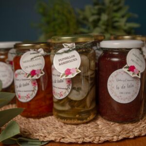 A collection of artisanal homemade jams and pickles in glass jars with floral labels.